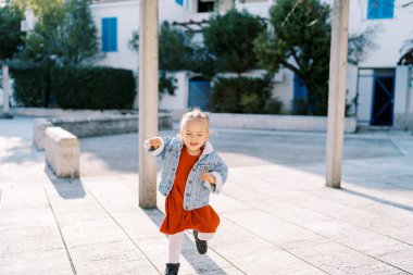 Küçük gülen kız evin yakınındaki fayanslı avluda koşuyor. Yüksek kalite fotoğraf