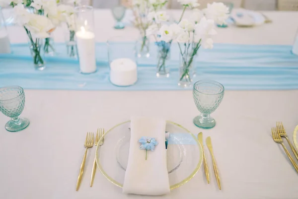 Blue flower lies on a napkin with an invitation on a plate on a set holiday table. High quality photo