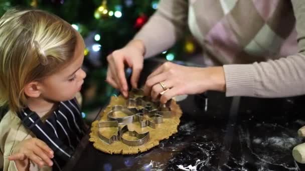 小さな女の子は母親が生地にクッキーカッターを置くように見ています 高品質の4K映像 — ストック動画