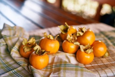Olgunlaşmış hurma, ahşap bir masanın üzerindeki buruşmuş kareli masa örtüsünde yatıyor. Yüksek kalite fotoğraf