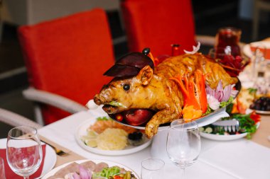 Kızarmış küçük domuz bir restoranda aperatiflerin yanında bir tabakta yatıyor. Yüksek kalite fotoğraf