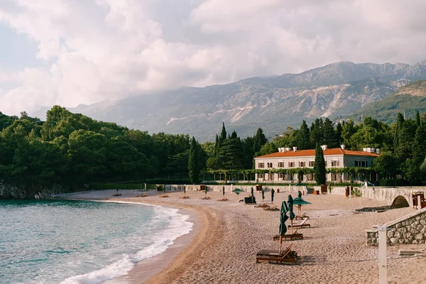 stock image Sun loungers with folded sun umbrellas stand on the sandy beach near Villa Milocer. Montenegro. High quality photo