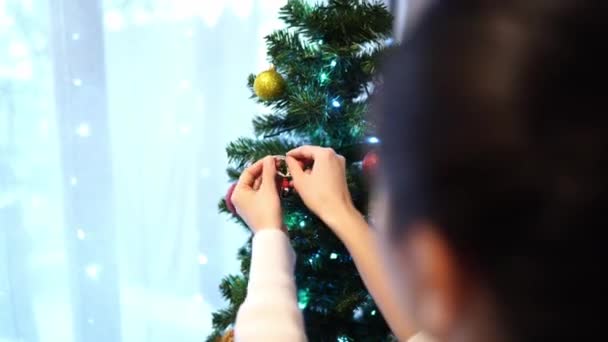 年轻的女人把一个雪人的雕像挂在一棵圣诞树的绿枝上 高质量的4K镜头 — 图库视频影像