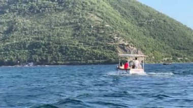 Turistlerle dolu tekne yeşil dağlara doğru denizde yüzüyor. Arkadan bak. Yüksek kalite 4k görüntü