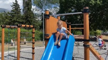 Little girl slides down the slide at the playground. High quality 4k footage