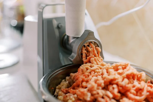 Electric meat grinder twists meat into a pan on the table. High quality photo
