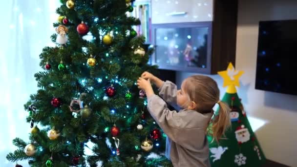 小女孩把玩具房子的雕像挂在圣诞树上 高质量的4K镜头 — 图库视频影像