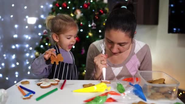 Little Daughter Eats Cookie While Watching Mom Decorating Cookies Icing — Stock Video