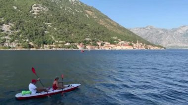 Turistler, yüksek bir dağ sırasının arka planına karşı körfez boyunca yelken açıyorlar. Yüksek kalite 4k görüntü