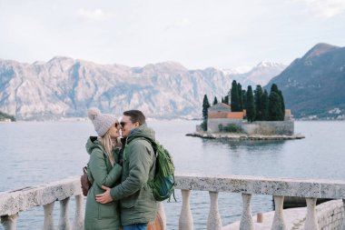 Erkek ve kız, St. George adasına tepeden bakan korkuluklara burunlarıyla sarılıyorlar. Karadağ. Yüksek kalite fotoğraf