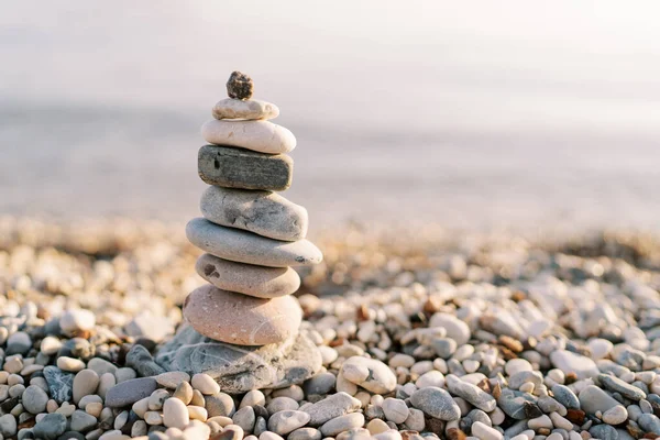 Cairn, güneşin altındaki çakıl taşı plajına gölge düşürüyor. Yüksek kalite fotoğraf