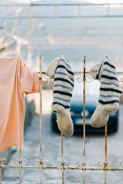 Washed T-shirt next to knitted socks dries on a metal grate. High quality photo