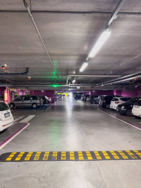 Aydınlatılmış bir yeraltı otoparkında sıra sıra bekleyen arabalar. Yüksek kalite fotoğraf