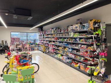 Küçük kız süpermarketin çocuk bölümünde rafların yanında oyuncaklarla duruyor. Yüksek kalite fotoğraf