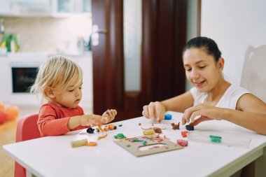 Annem ve küçük bir kız masada plasticine yapıyorlar. Yüksek kalite fotoğraf