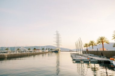 Gün batımında dağların arka planına demirlemiş yatları olan uzun paralel rıhtımlar. Yüksek kalite fotoğraf