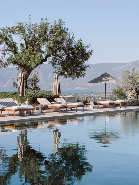 Şezlonglar ve güneş şemsiyeleri havuzun yanında. Amanzoe Oteli, Yunanistan. Yüksek kalite fotoğraf