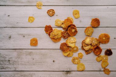 Meyve cipsleri hafif ahşap bir arka fonun köşesinde dağıtılır. Yüksek kalite fotoğraf