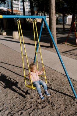 Parlak güneş ışığı altında sallanan küçük kız. Yüksek kalite fotoğraf