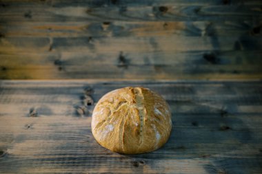 Ekmek kabuğunda çizikler olan bir somun ekmek ahşap bir masanın üzerinde yatıyor. Yüksek kalite fotoğraf