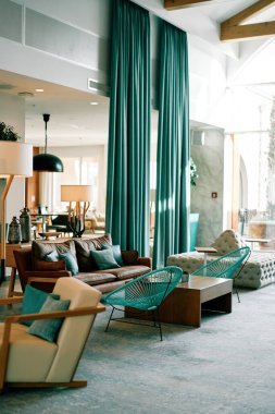 Kanepeleri, yeşil perdeleri ve yüksek pencereli masaları olan bir otel odası. Yüksek kalite fotoğraf