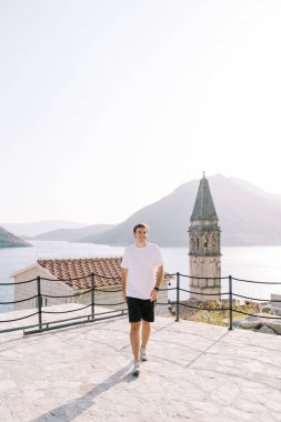 Gülümseyen adam kilisenin yanındaki gözlem güvertesinde yürüyor. Perast, Karadağ. Yüksek kalite fotoğraf