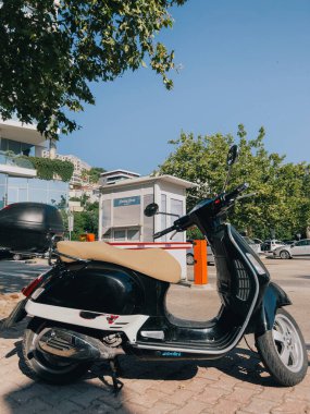 Ağacın yanındaki otoparkta bagajı olan küçük bir scooter. Yüksek kalite fotoğraf