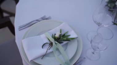 Kurdeleyle bağlanmış beyaz çay gülü masaya konmuş bir tabakta peçetenin üzerinde yatıyor. Yüksek kaliteli FullHD görüntüler
