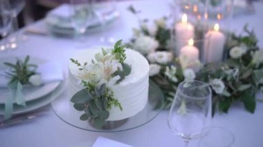 Düğün pastası yanan mumların yanındaki masada duruyor. Yüksek kaliteli FullHD görüntüler
