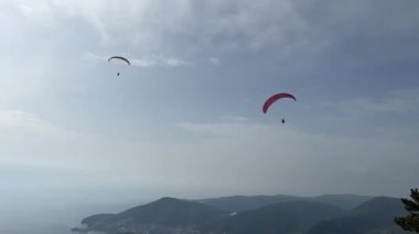 Paraşütle atlayan paraşütçüler bir dağ sırasının üzerinde uçuyor. Yüksek kalite 4k görüntü