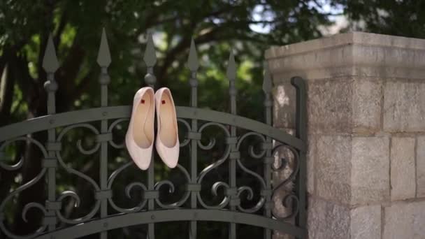 Παπούτσια Της Νύφης Κρέμονται Στον Σιδερένιο Φράχτη Του Κήπου Κοντινό — Αρχείο Βίντεο