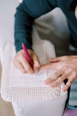 Damat koltukta otururken bir kağıt parçasına evlilik yemini yazar. Kırpılmış. Yüzsüz. Yüksek kalite fotoğraf