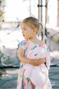 Pembe pelüş tavşanlı küçük kız başını yana çevirmiş duruyor. Yüksek kalite fotoğraf