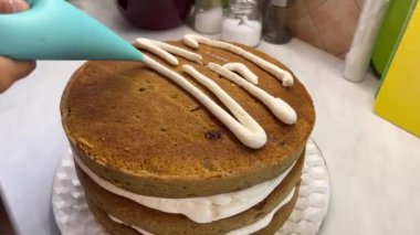 Pastacı pastaya pasta poşetinden krema şeritleri yapıştırıyor. Yüksek kalite 4k görüntü