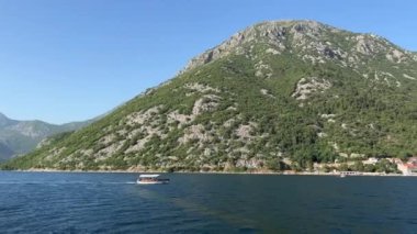 Keşif teknesi dağlık sahil boyunca denizde yüzer. Yüksek kalite 4k görüntü