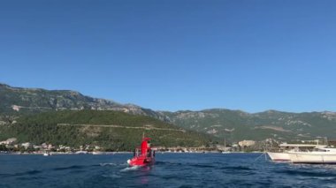 Kırmızı motorlu tekne dağlık bir sahile doğru deniz boyunca yüzer. Arkadan bak. Yüksek kalite 4k görüntü