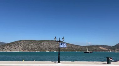 Yunan bayrağı, deniz kıyısındaki bir fenerde rüzgarda dalgalanıyor. Yüksek kalite 4k görüntü