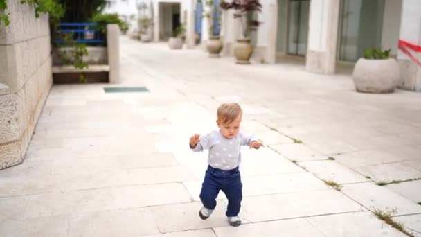小さな子供が家のタイル張りの庭を歩き 手でバランスをとっています 高品質4K映像 — ストック動画