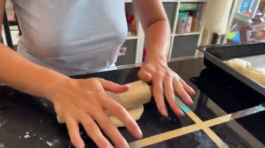 Baker ekmeğin hamurunu masanın üzerinde merdaneyle yuvarlıyor. Yüksek kalite 4k görüntü