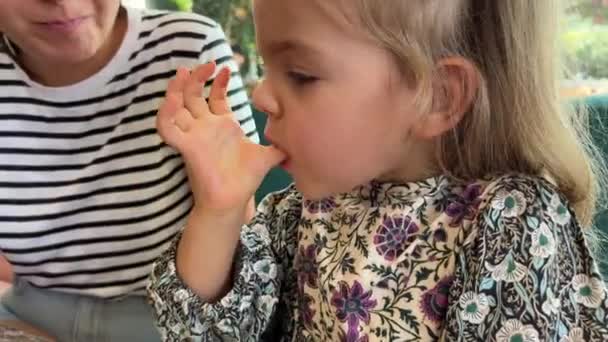 Little Girl Licks Fingers While Eating Blueberry Biscuit Cake High — Stock Video