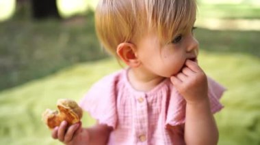 Küçük kız battaniyeye oturur ve yavaşça krep çiğner. Yüksek kalite 4k görüntü