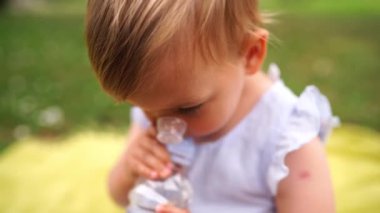 Küçük kız dökülmemiş kapaklı bir şişeden su içiyor. Yüksek kalite 4k görüntü