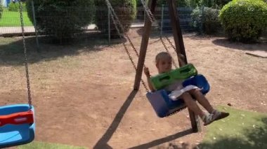 Küçük kız bahçede zincirli salıncakta sallanıyor. Yüksek kalite 4k görüntü