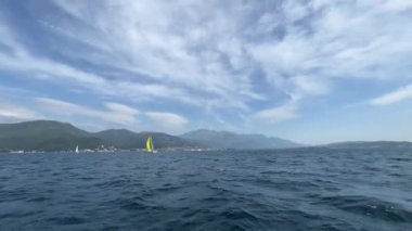 Sarı yelkenli bir yat bir dağ sırası boyunca deniz boyunca yüzer. Yüksek kalite 4k görüntü