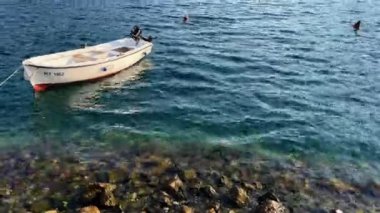 Balıkçı teknesi dalgalar üzerinde dalgalanan kayalık bir kıyıya demirledi. Yüksek kalite 4k görüntü