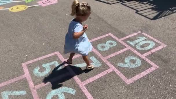 Kleines Mädchen Springt Den Hopscotch Der Auf Dem Bürgersteig Gemalt — Stockvideo