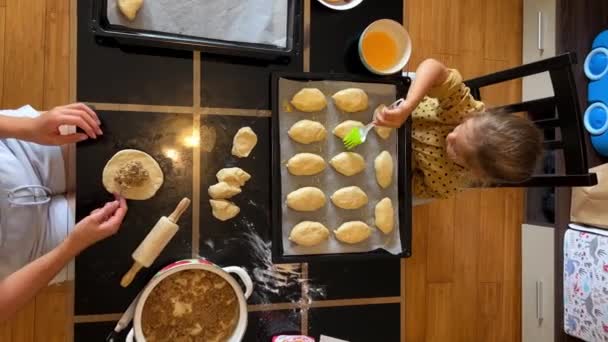 妈妈把填好的面包放进面包里 小女孩用打好的鸡蛋刷着面包 高质量的4K镜头 — 图库视频影像