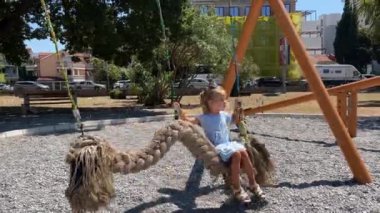 Küçük kız salıncakta sallanıyor. Parkta örgü şeklinde. Yüksek kalite 4k görüntü