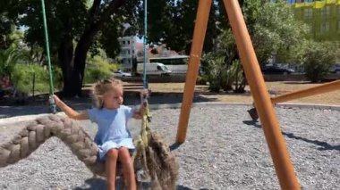 Küçük kız hasır bir iple sallanıyor ve saç örgüsü şeklinde sallanıyor. Yüksek kalite 4k görüntü