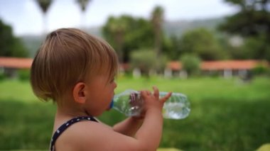 Küçük kız şişeden su içiyor. Yan görüş. Yüksek kalite 4k görüntü